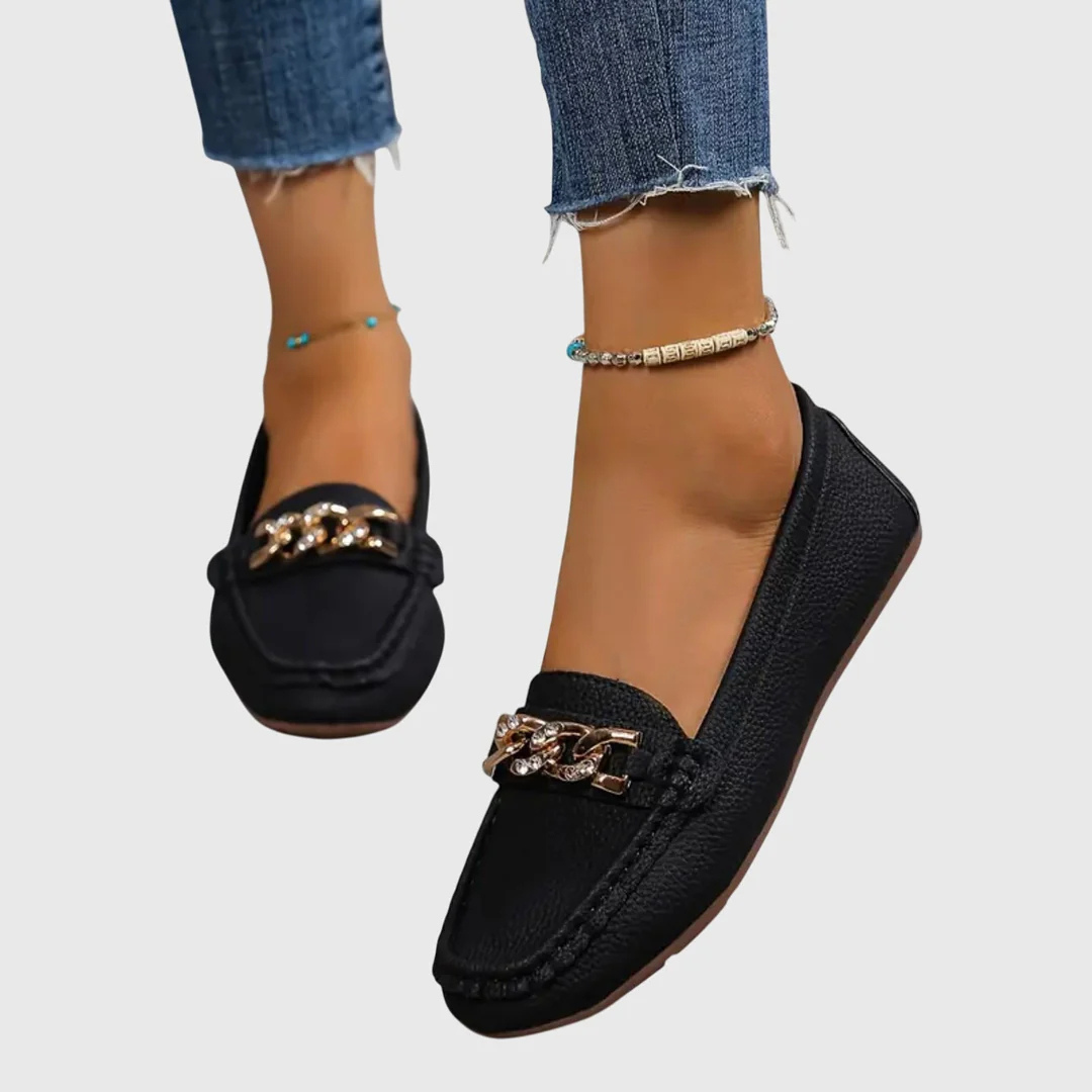 Nahaufnahme der eleganten Kette auf schwarzen Damen Loafern. Stilvolle Details für modische Frauen.
