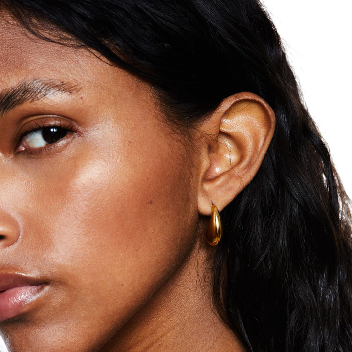 Detailansicht der glänzenden goldenen Tropfen-Creolen, hochwertiger Edelstahl-Schmuck für Damen.