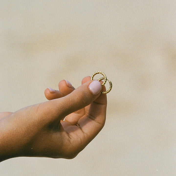 Schimmernde goldene gehämmerte Creolen für Damen. Wasserfester, hypoallergener Edelstahlschmuck.