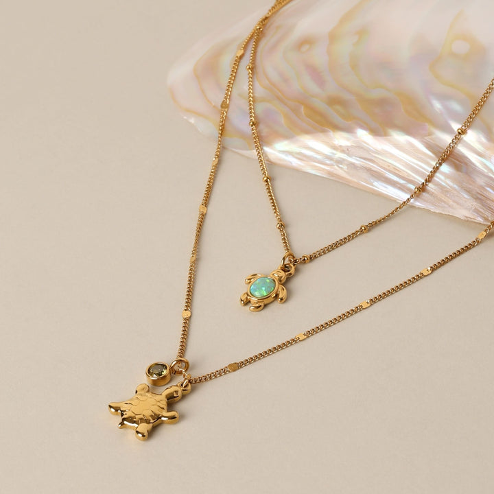 Nahaufnahme eines goldenen Schildkröten Opalanhängers an einer zarten Damen Halskette, maritim.