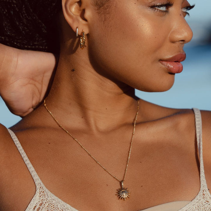 Detailaufnahme der goldenen Damen Halskette mit Sonnen-Symbol. Wasserfest und stilvolles Accessoire.