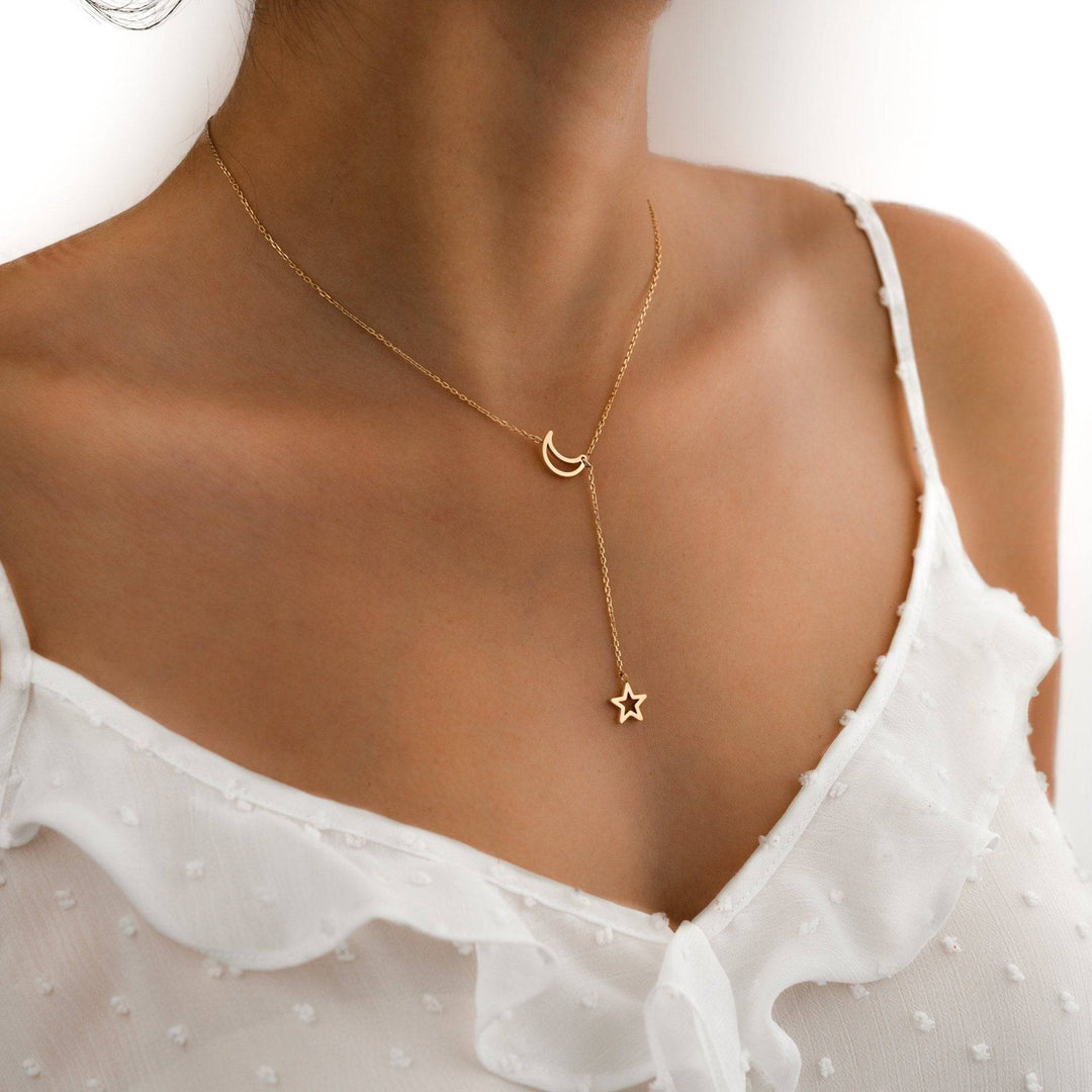 Detailaufnahme einer zarten Damen Sternenlicht-Halskette mit glänzenden Mond- und Stern-Anhängern, Schmuck.