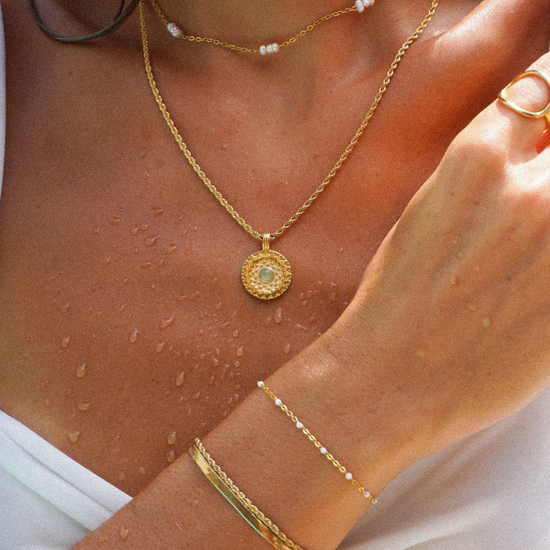 Verstellbare Gold Halskette für Damen mit grünem Aventurin Edelstein und detailliertem Sonnenmotiv aus Edelstahl.