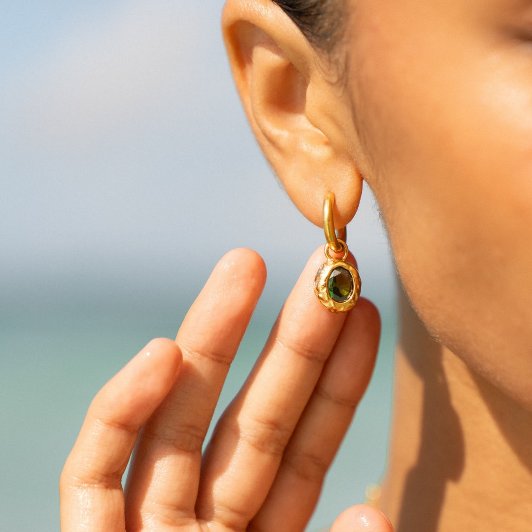 Stylische goldene Damenohrringe (Creolen) mit grünem Zirkon am Ohr. Hypoallergen & wasserfest.