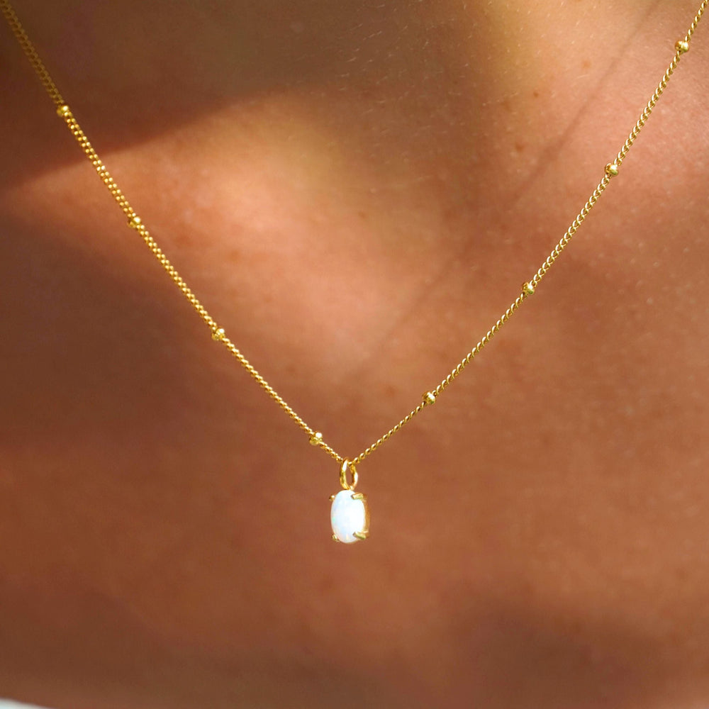 Nahaufnahme des zierlichen Goldanhängers mit schillerndem, echtem Opal für Damen, wasserfest.