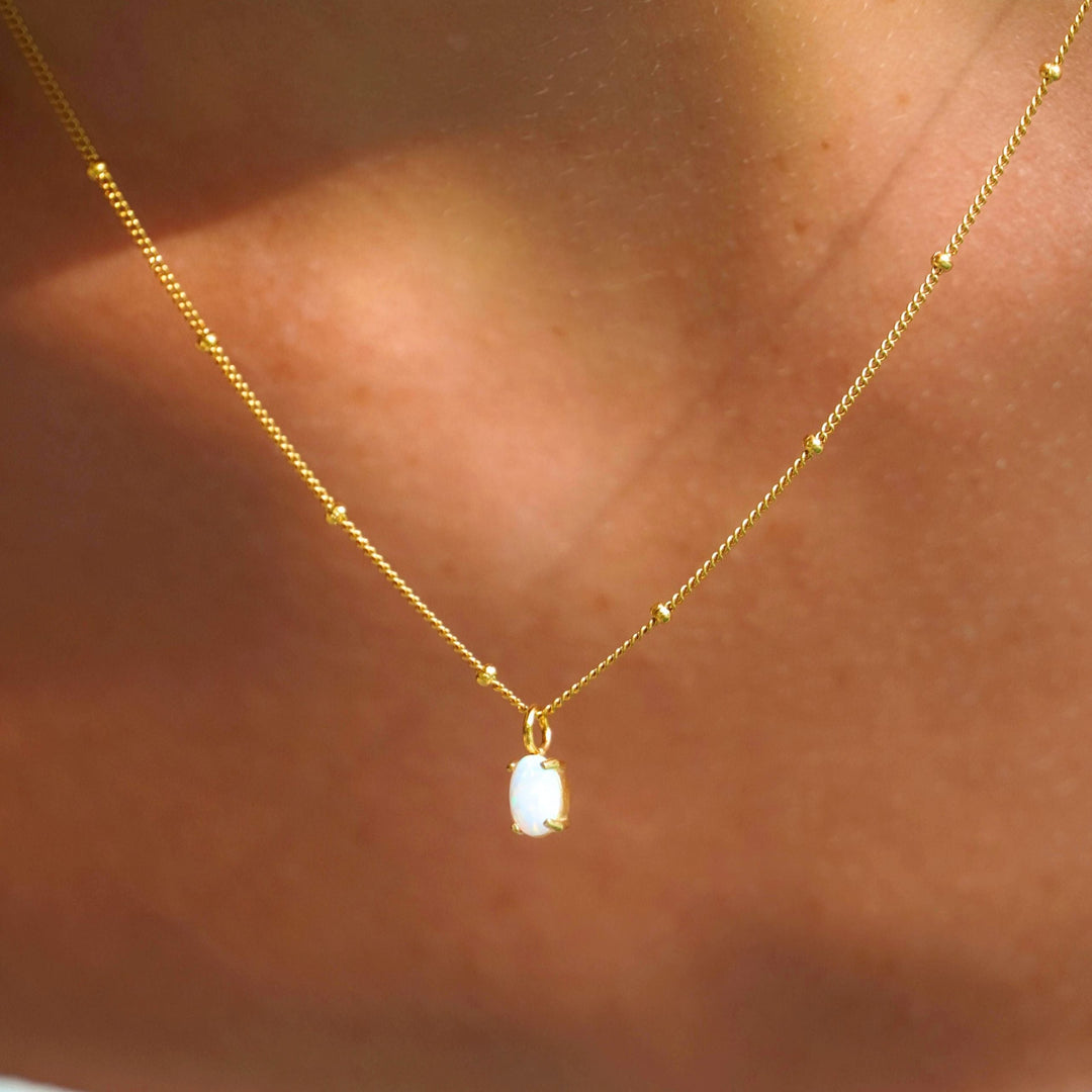 Nahaufnahme des zierlichen Goldanhängers mit schillerndem, echtem Opal für Damen, wasserfest.