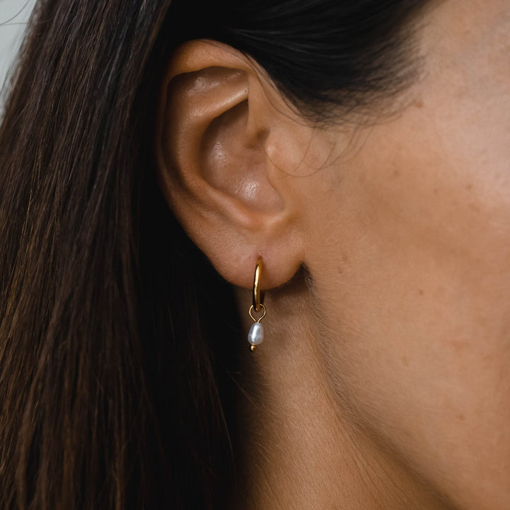 Silberne Damen Huggie Ohrringe mit glänzenden Süßwasserperlen. Moderner wasserfester Schmuck.