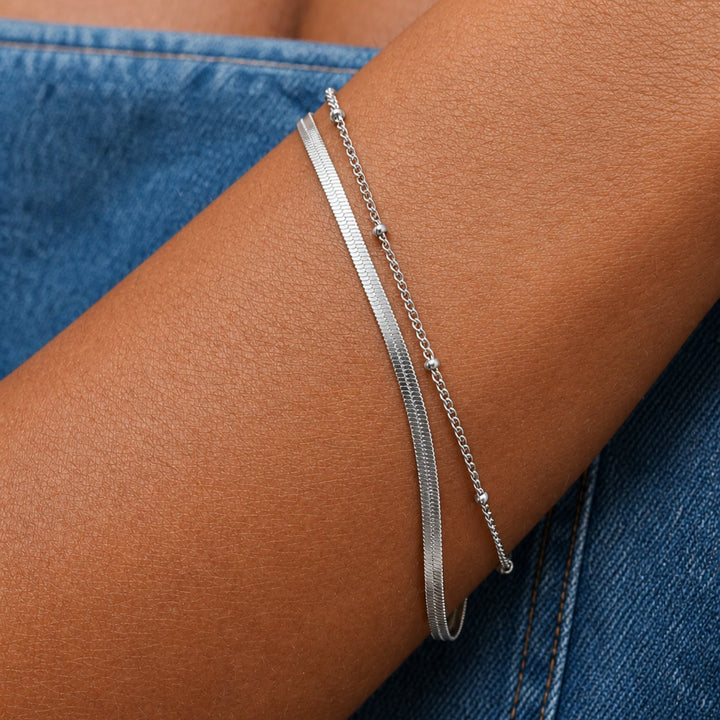 Schickes Damen Layering Armband in Gold. Herringbone Gliederkette und zarte Perlenkette. Wasserdichter verstellbarer Schmuck.