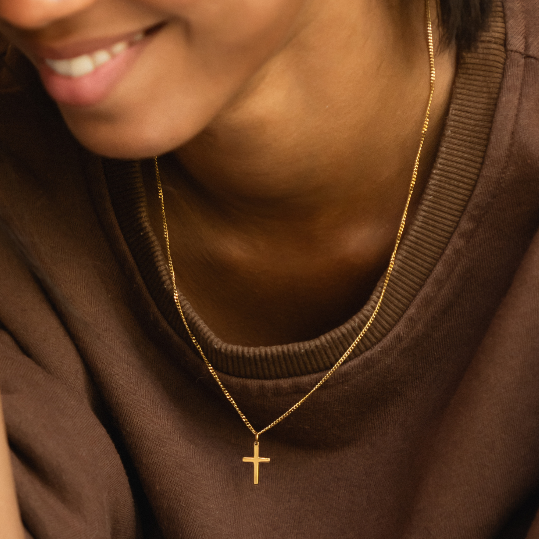 Nahaufnahme: Zarte goldene Kreuzkette aus wasserdichtem Edelstahl. Minimalistischer Damenschmuck, perfekt für Layering.