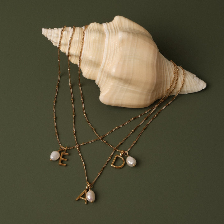 Close-up: Goldhalskette für Damen mit schimmernder Barockperle & glänzendem Initial Anhänger.