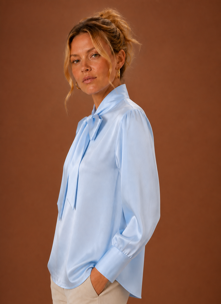 Nahaufnahme der eleganten Schleife an einer weißen Damen-Bluse in glänzender Satin-Optik.
