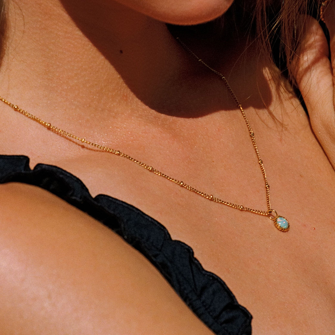 Nahaufnahme eines eleganten Opal-Anhängers an einer goldenen Edelstahlkette, hypoallergen und wasserfest.