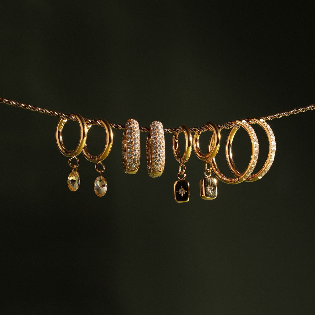 Detailaufnahme der goldenen Damen Creolen mit feinem Sternanhänger und glitzerndem Zirkonia.