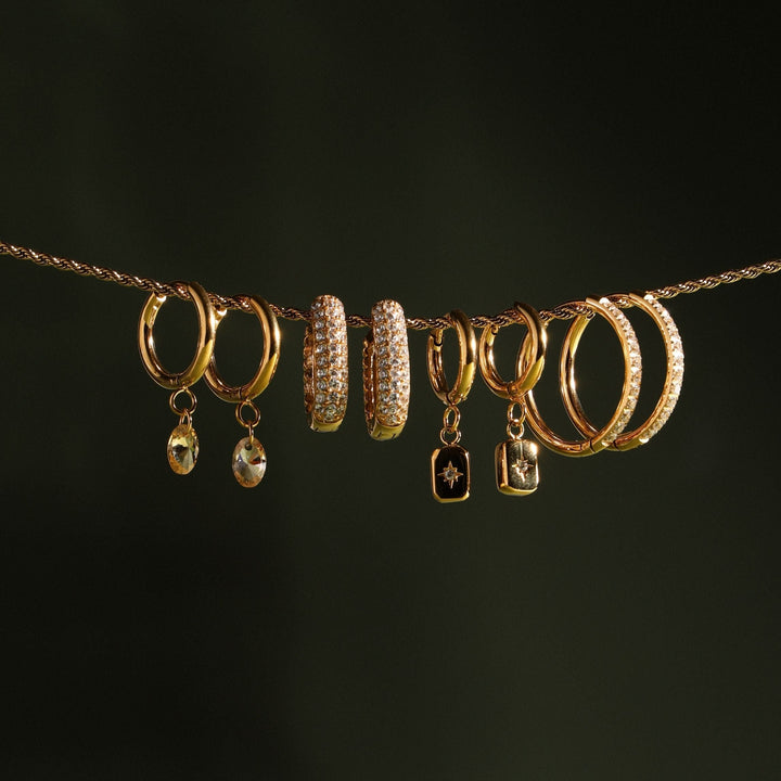 Detailaufnahme der goldenen Damen Creolen mit feinem Sternanhänger und glitzerndem Zirkonia.