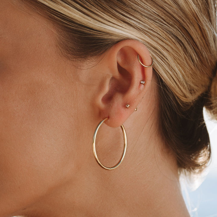 Minimalistische dünne Creolen für Damen, wasserfest & hypoallergen, in glänzendem Gold oder Silber.