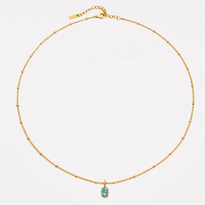 Nahaufnahme der goldenen Damenkette mit glänzendem Türkis-Anhänger und Perlen, hochwertiger Edelstahlschmuck.