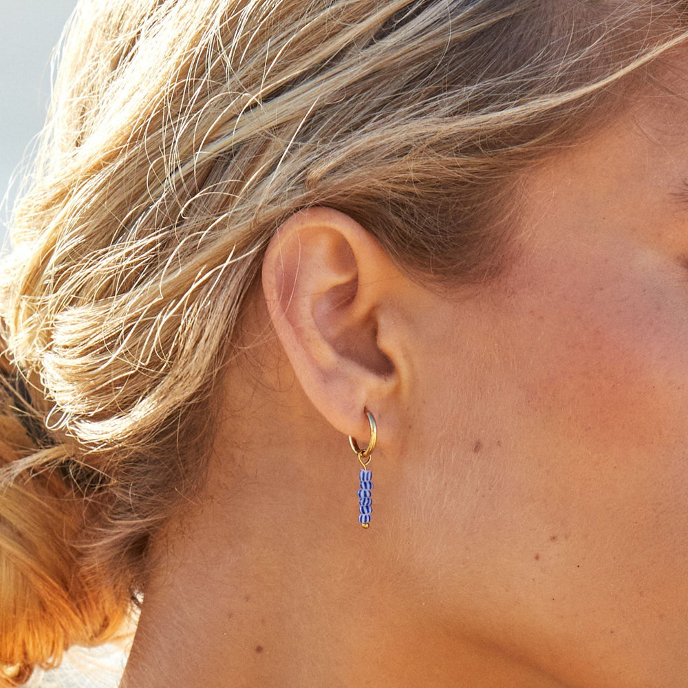 Elegante goldene Damen-Creolen mit blauen Perlen. Wasserfester & hautfreundlicher Edelstahlschmuck.