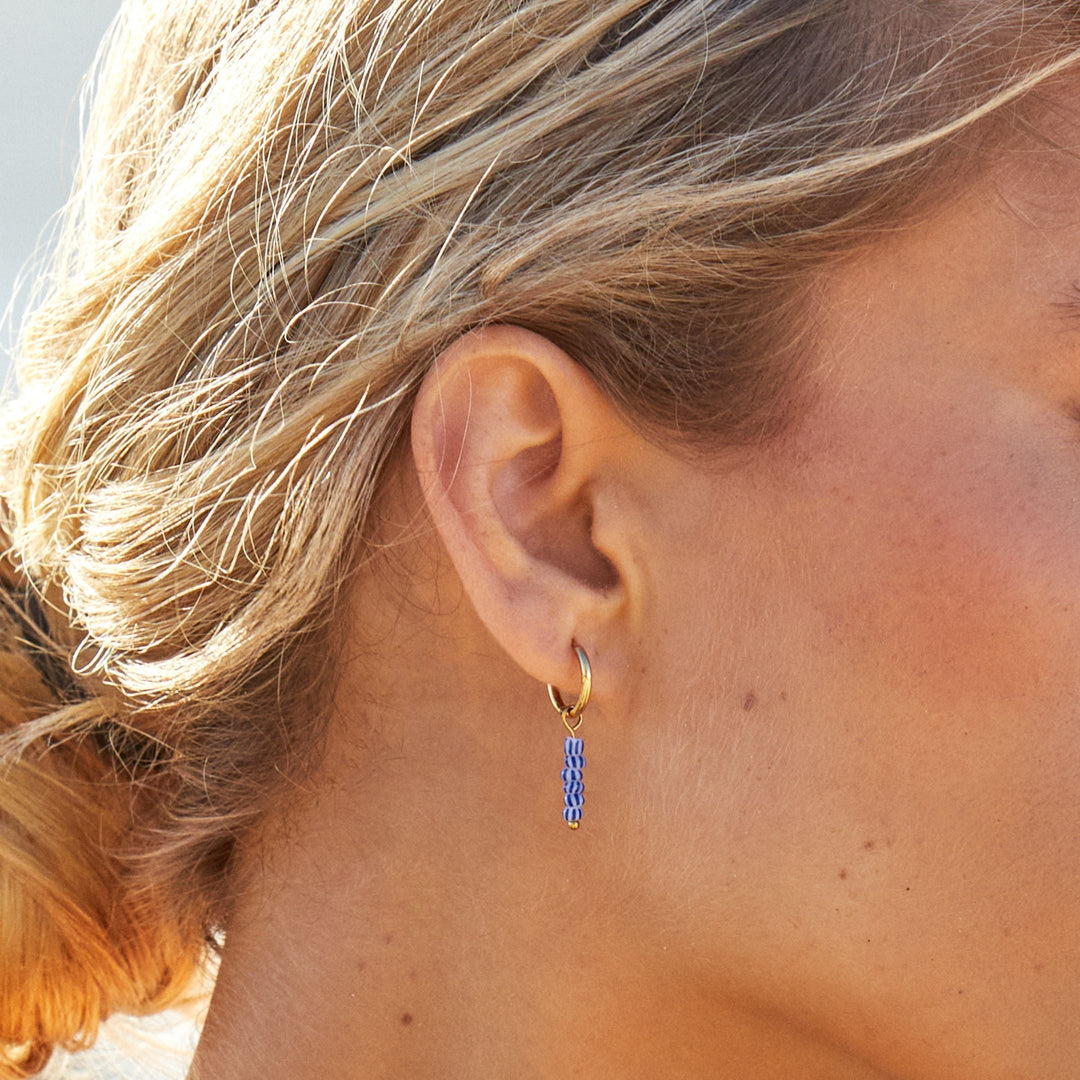 Elegante goldene Damen-Creolen mit blauen Perlen. Wasserfester & hautfreundlicher Edelstahlschmuck.