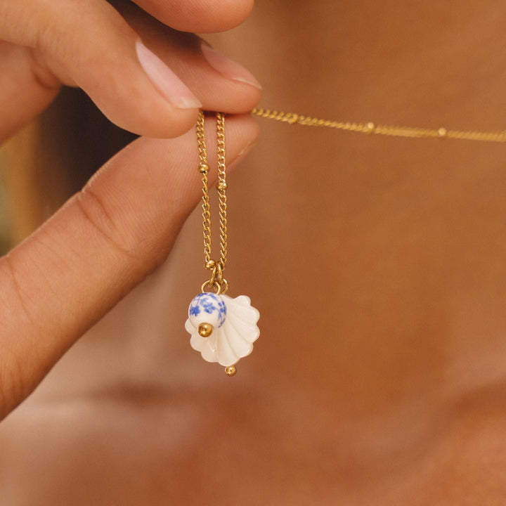 Nahaufnahme einer Perlmutt Muschel & Keramikperle an einer glänzenden Damen Edelstahl Halskette.
