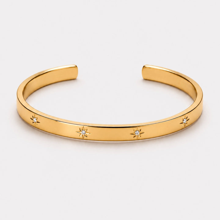 Nahaufnahme des goldfarbenen Damenarmreifs mit filigranen Sternmotiven und glänzenden Zirkonsteinen. Hypoallergen.