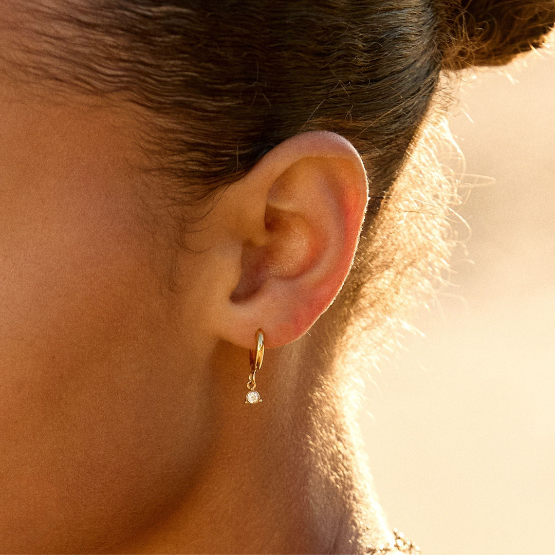 Elegante goldfarbene Damen Huggie Creolen mit glitzernden Zirkonia Steinen, wasserfest & hypoallergen.