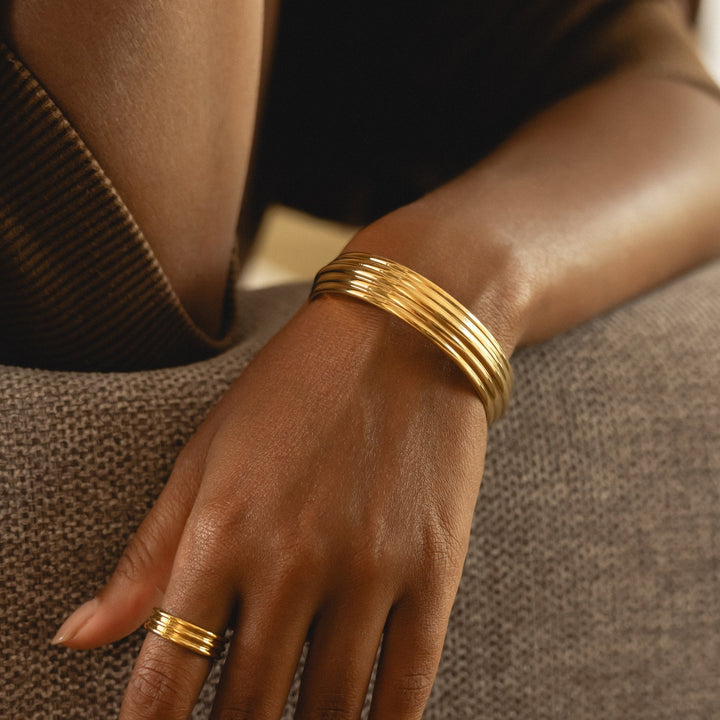 Moderner Gold Armreif für Frauen, breit und skulptural, aus hypoallergenem Edelstahl, verstellbar.